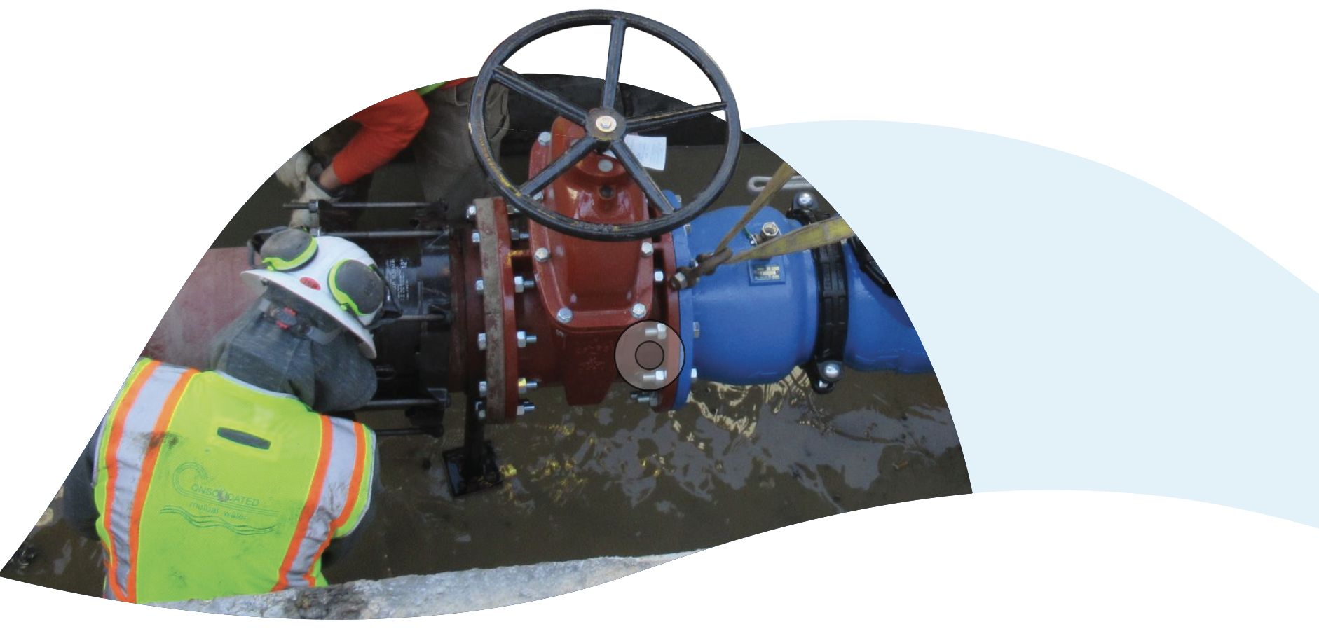 CMWC worker in high-visibility vest and hard hat working on large red and blue pipe valves in an underground excavation